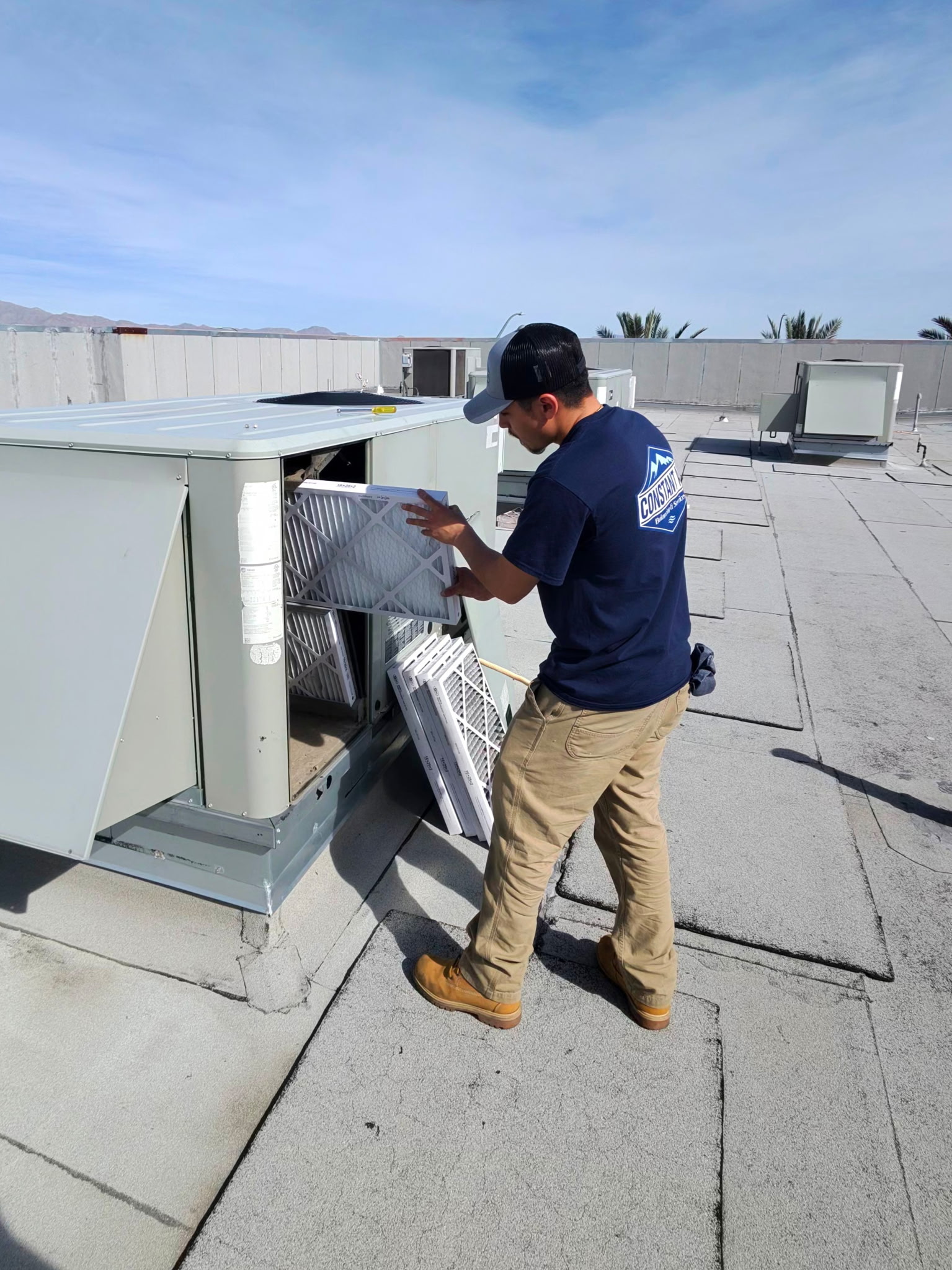Constant Air Balancing technician changing filters on a commercial rooftop HVAC unit in Las Vegas, NV